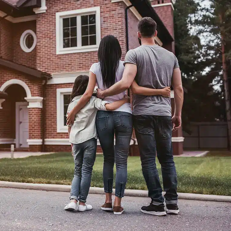 a family of three standing in front of their newly purchased home