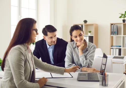 a real estate agent showing two home buyers a laptop screen