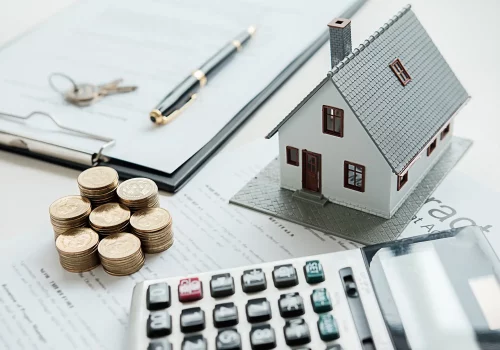 a small model of a house next to a set of keys on a table