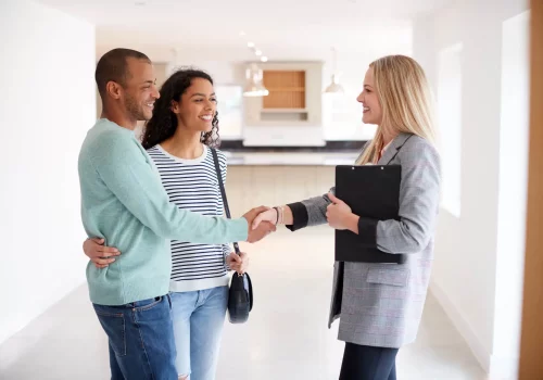 two home buyers shaking hands with a real estate agent