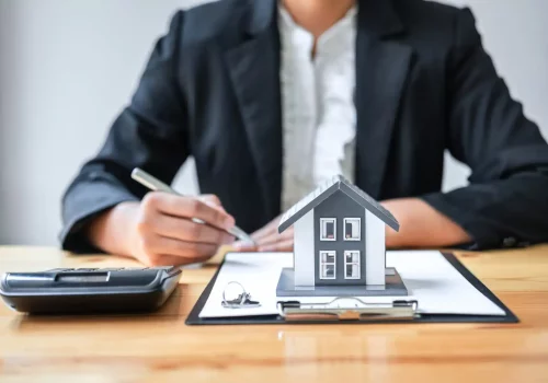 a small model of a house on top of a table with a realtor in the background