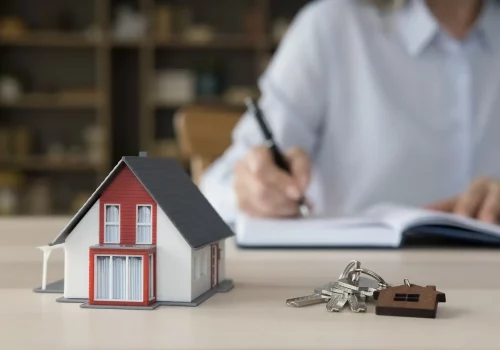 a small model of a house next to a set of keys on a table