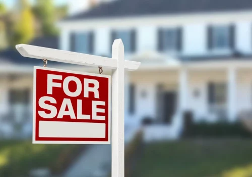 a for sale sign in front of a large home